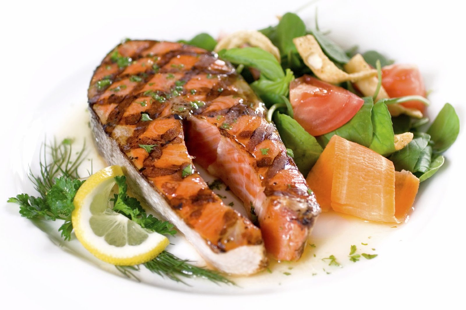 Delicious salmon steak grilled to perfect and served with a colorful side salad of wild greens.  Shallow dof.